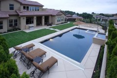 A pool with a waterfall in a luxury backyard with new landscaping
